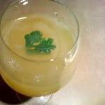 A top down shot of Aam Panna in a glass, garnished with a green herb