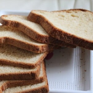 A pear carrot and oats bread loaf sliced on top of a white plate
