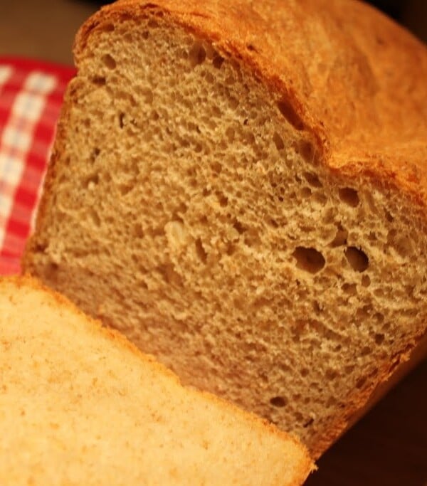 A potato bread loaf cut into slices on a red and white cloth