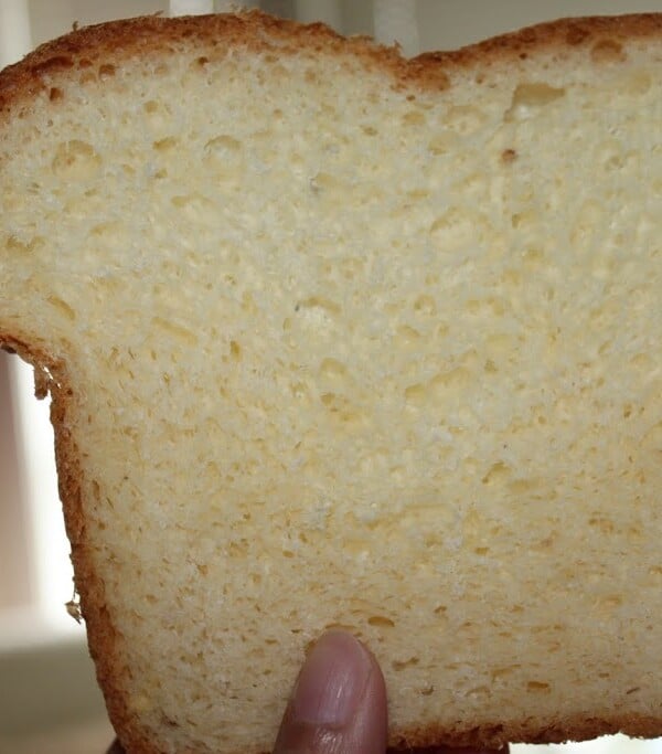 A slice of white sandwhich loaf being held towards the camera
