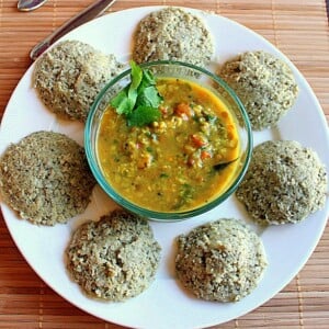 Steamed rice cakes on a white plate with an orange dip