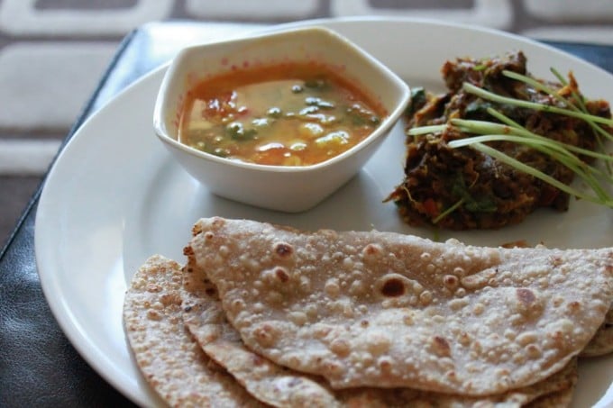 Baingan Bharta, sambhar, roti and papad sweved together on a white plate