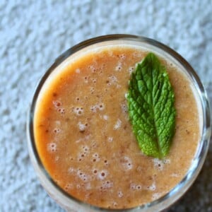 A top down shot of a mango strawberry mint cooler, garnished with a mint leaf