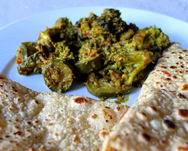 Broccoli and Zucchini in Onion and Pickle Spices served on a plate with roti