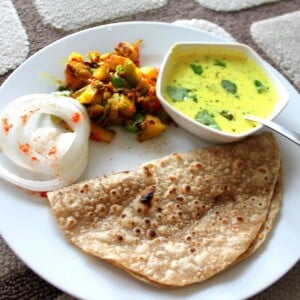 Tempered Cashew Yogurt, Spiced Potatoes and Bell Peppers with Indian Flat Bread served together on a white plate
