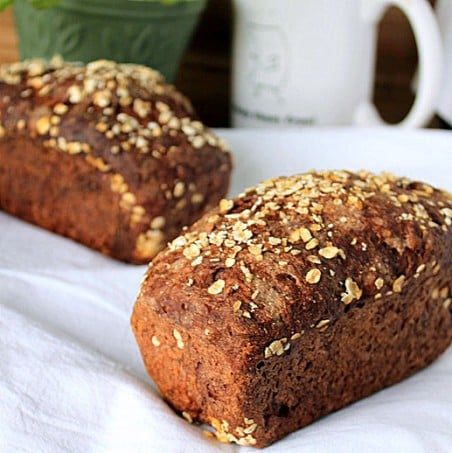 Two chocolate multigrain mini loaves on white fabric