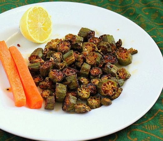 Crisp okra on a white plate werved with a lemon wedge and carrot sticks