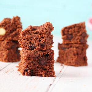 Vegan chocolate brownies stacked on a white wooden work surface