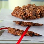 A stack of chocolate oatmeal raisin cookies separated by parchment paper