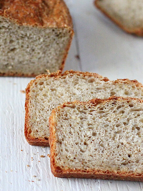 Pear Quinoa Chai spice Bread loaf with slices cut on a white wooden background.