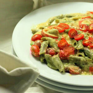 A white shallow bowl, filled with Spinach Penne with Red Bell peppers