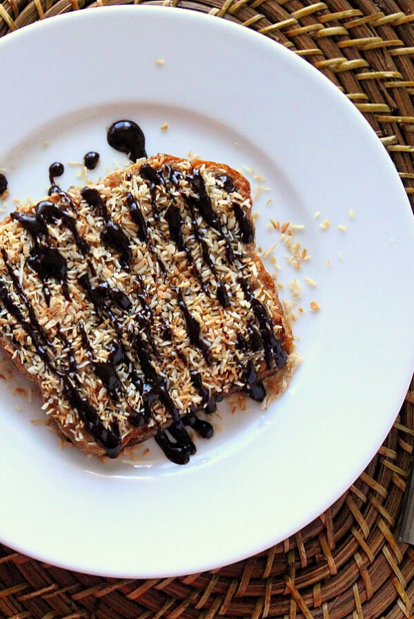 A slice of french toast on a white plate, drizzled with chocolate