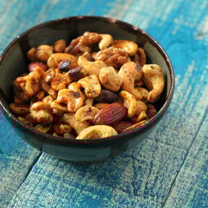 A bowl of spiced roasted nuts on a blue wood background
