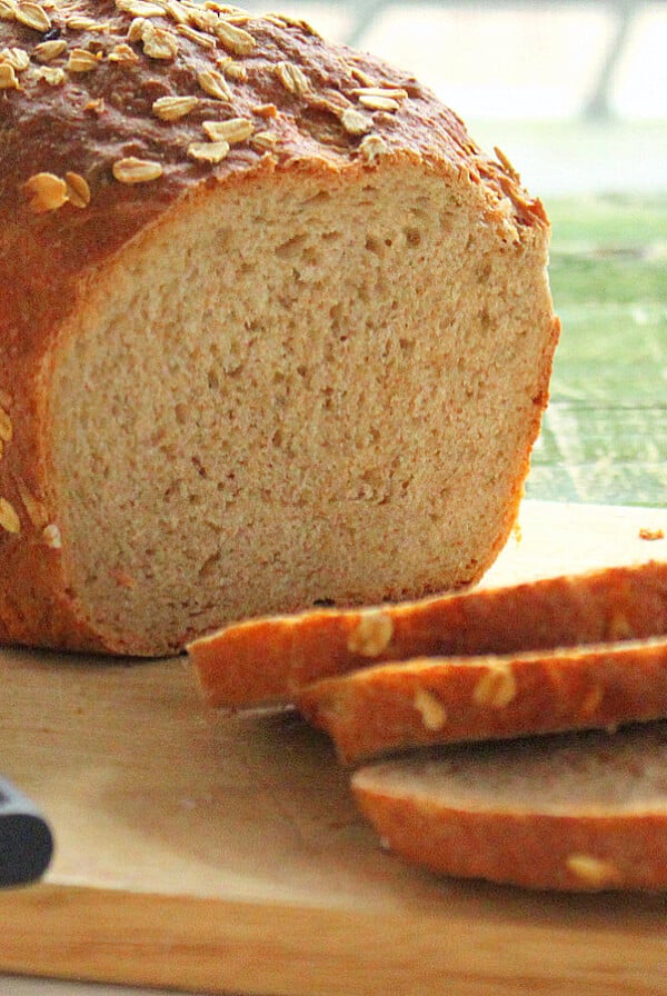 A sliced loaf of cherry amaretto bread on a wooden chopping block
