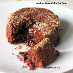 A molten lava cake on a white plate. A piece is broken away to show the melted chocolate centre