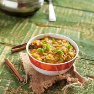 A bowl of red lentil stew on a green background