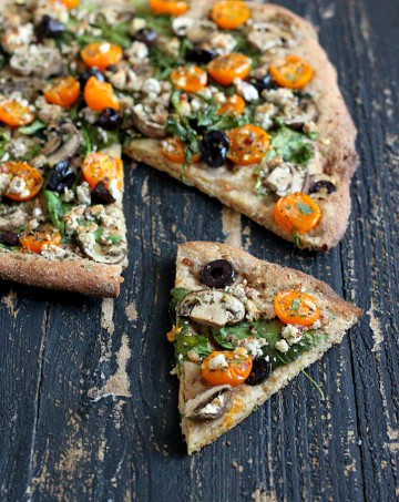 Almond Feta, Mushroom, greens, olives, golden cherry tomatoes. Vegan Mediterranean Pizza with Thin Herbed Spelt Crust. vegan recipe