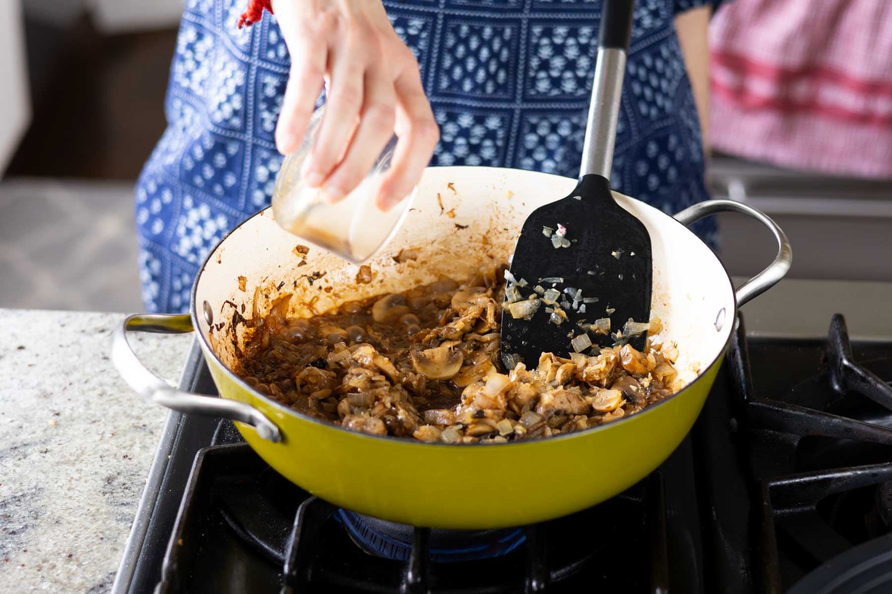 adding broth to the pan