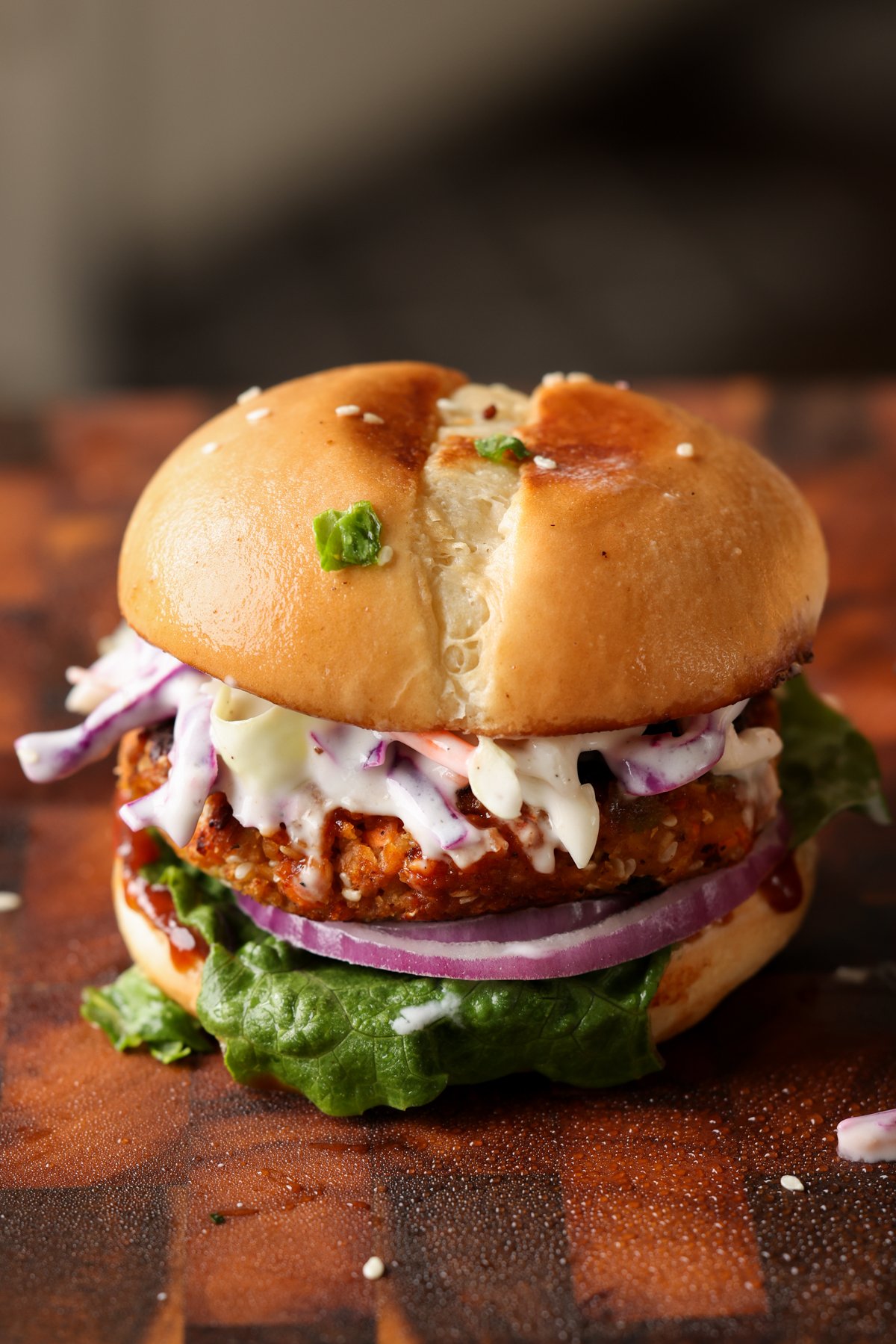 BBQ lentil burger in a bun with lettuce, tomato, onion, and slaw