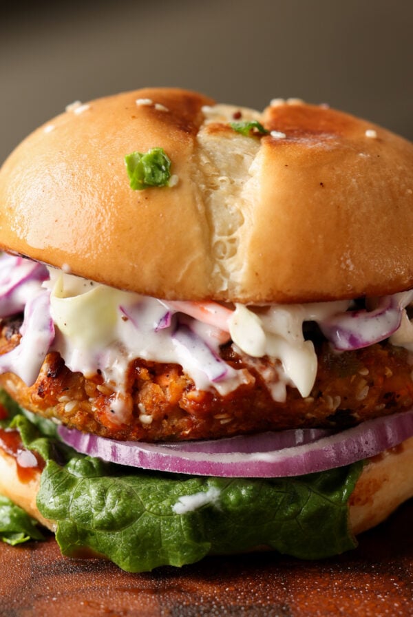 BBQ lentil burger in a bun with lettuce, tomato, onion, and slaw