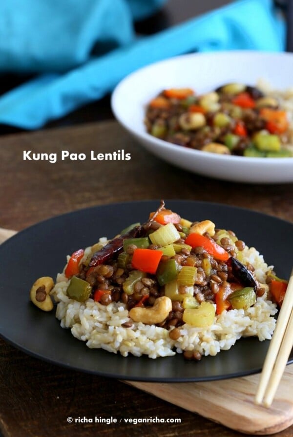 Kung Pao Lentils over brown rice on a black plate with chopsticks