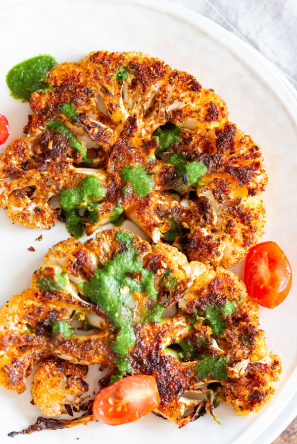 Vegan Cajun Roasted Cauliflower "Steaks" with Chimichurri Sauce. Slice into thick slices or just chop into florets to make this delicious Cajun Cauliflower. Serve with chimichurri or a cooling dressing. #Vegan #Glutenfree #Soyfree #Nutfree #Recipeย #veganRicha #cajunCauliflower