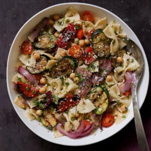 serving bowl of summer pasta salad with grilled vegetables with a spoon in it