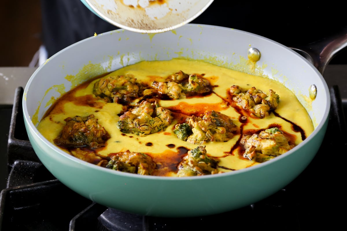drizzling the chili oil over the pan of kadhi pakora