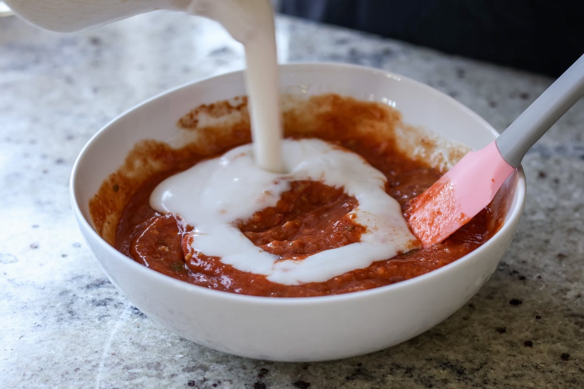 adding the remaining coconut milk after mixing in the tomato paste