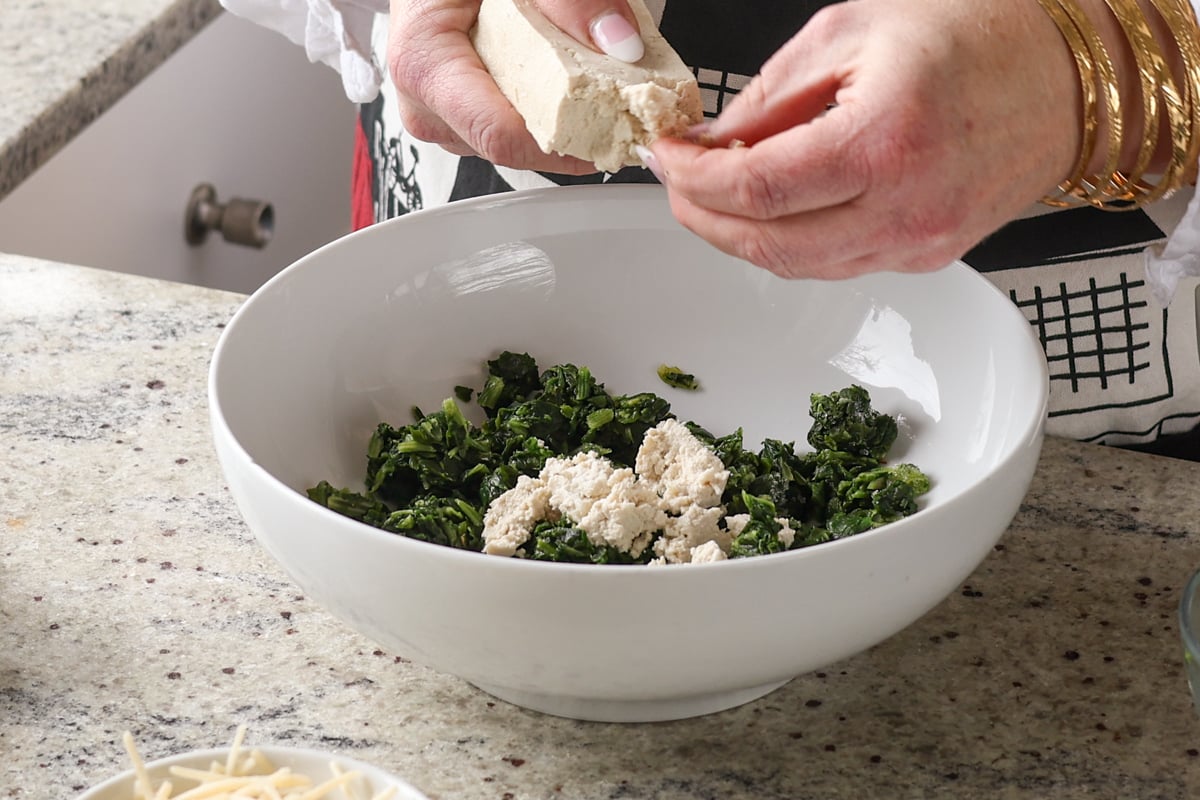 crumbling tofu into the bowl of spinach