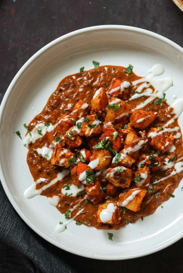paneer ghee roast on a plate with yogurt and cilantro