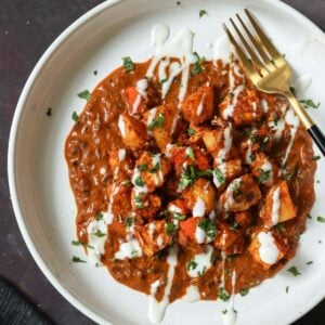 paneer ghee roast on a plate with yogurt and cilantro