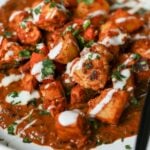 close-up of paneer ghee roast on a plate with yogurt and cilantro