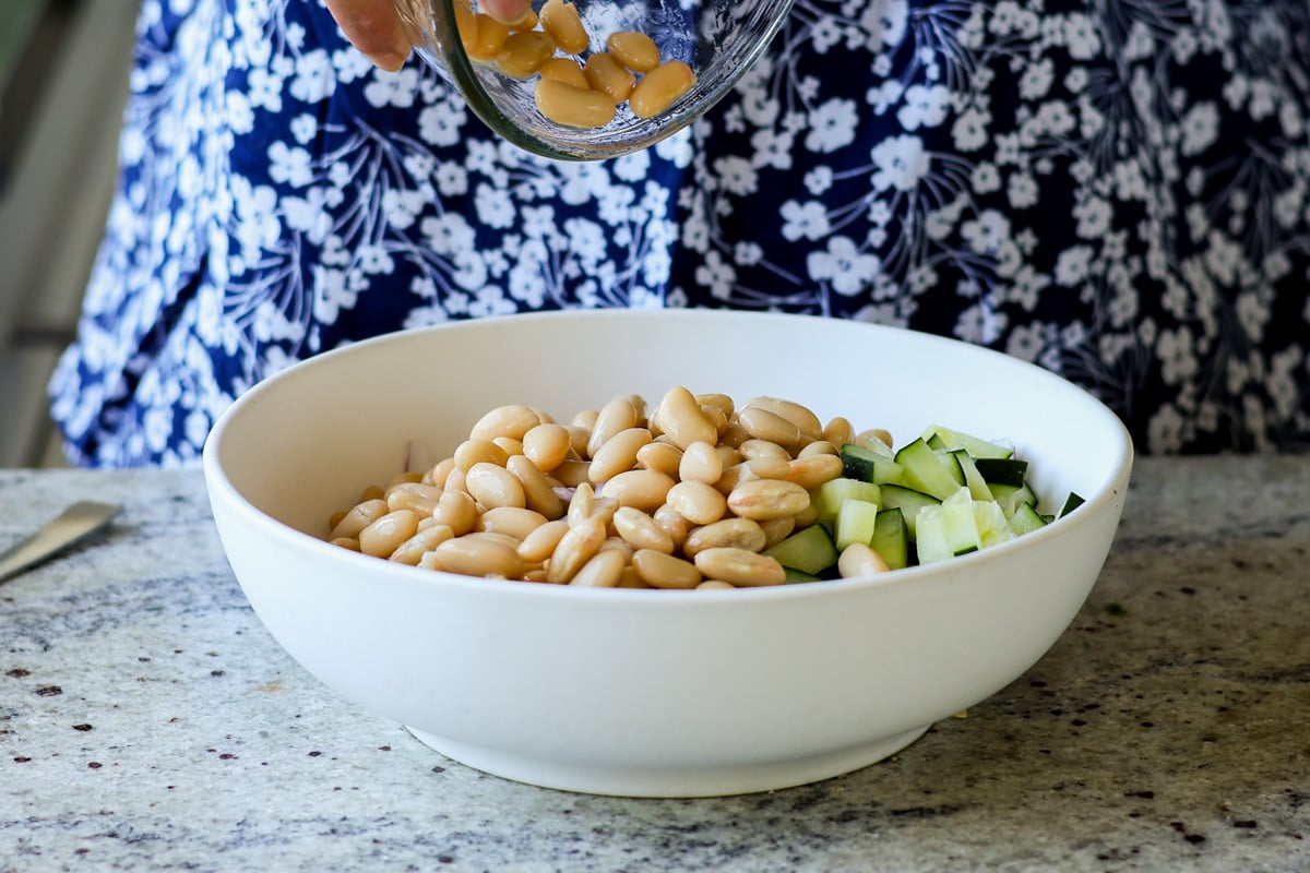 adding beans to the bowl of veggies