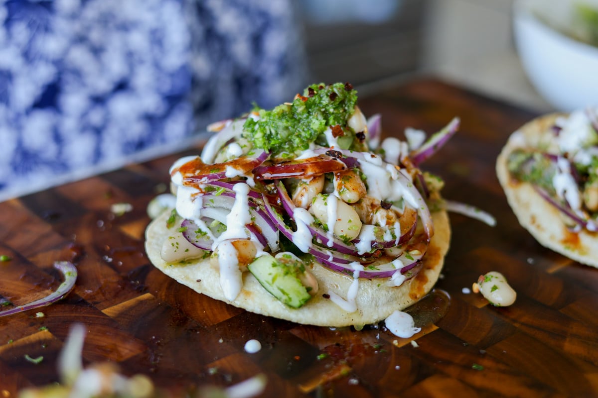 adding garnishes to the chutney white bean tostadas