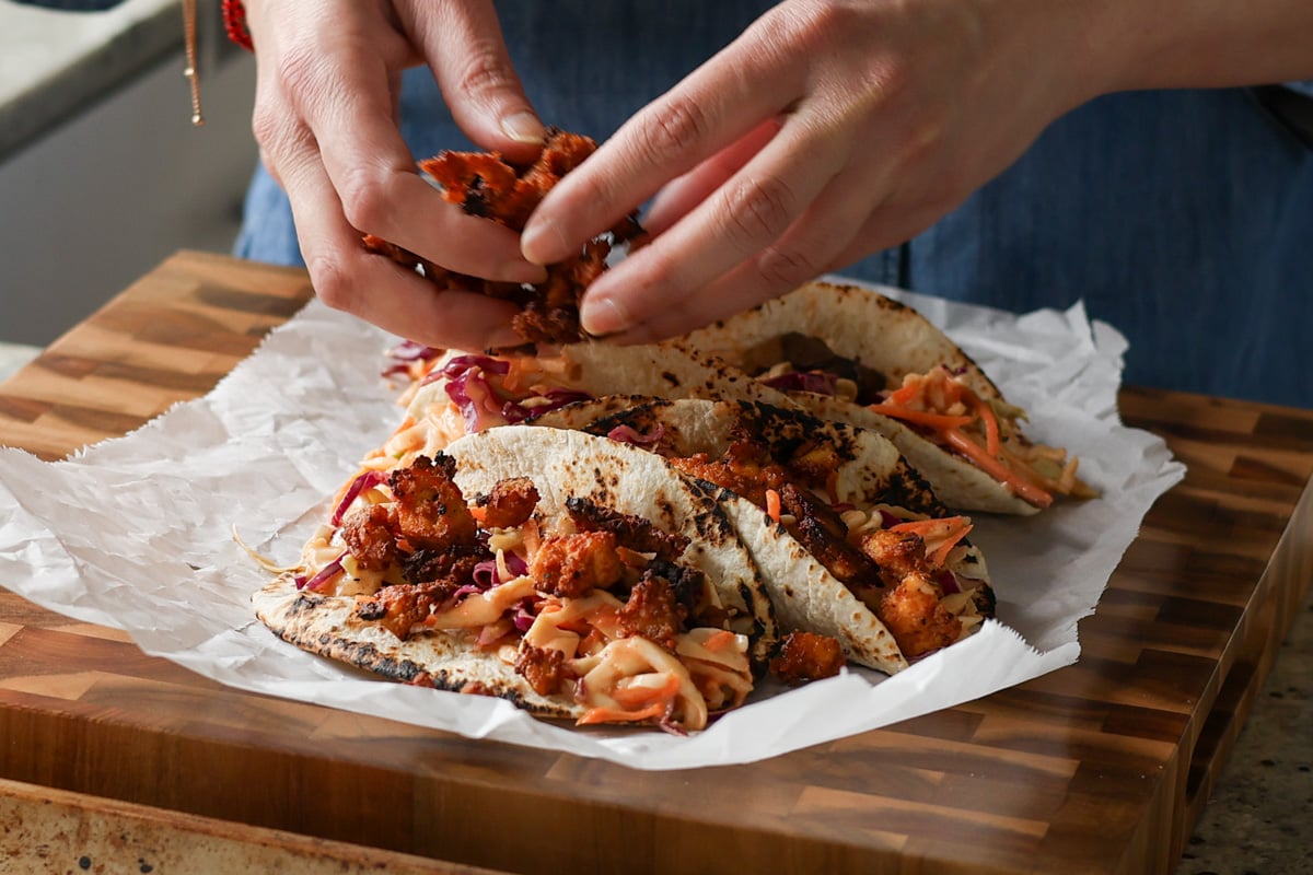 adding the gochujang tofu to the tacos