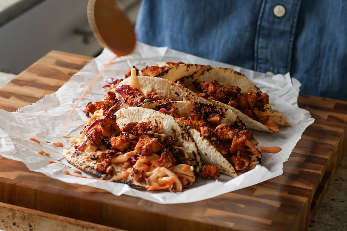 adding yum sauce to the gochujang tacos