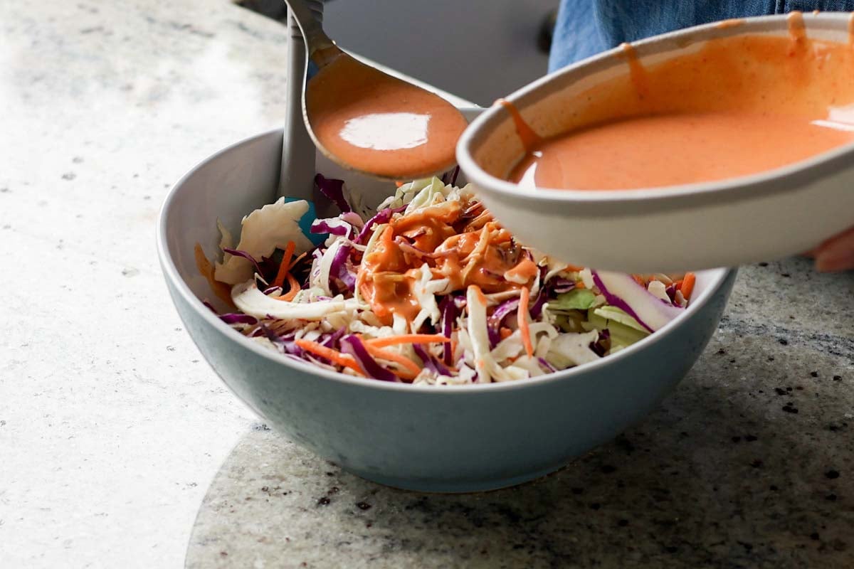 adding yum sauce to the slaw mixture