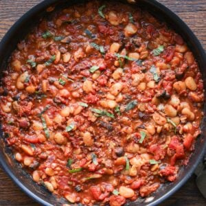 pan of puttanesca beans on a wooden table