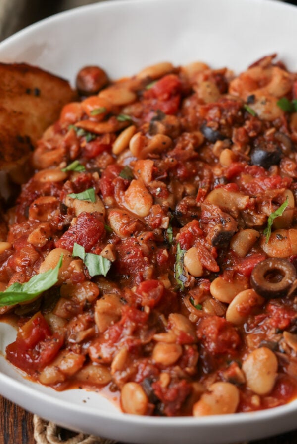 puttanesca beans on a plate with garlic bread