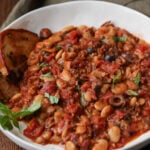 puttanesca beans on a plate with garlic bread