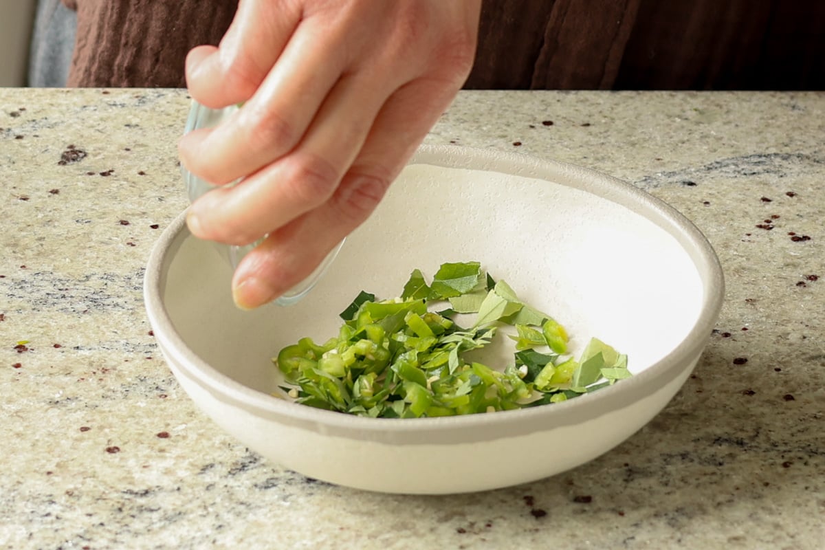adding the chilis and curry leaves to a bowl