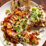 sheet pan veggies and beans over creamy lemon yogurt sauce on a white plate with bread for dipping