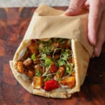 hand picking up a wrap made from making a wrap from sheet pan veggies and beans