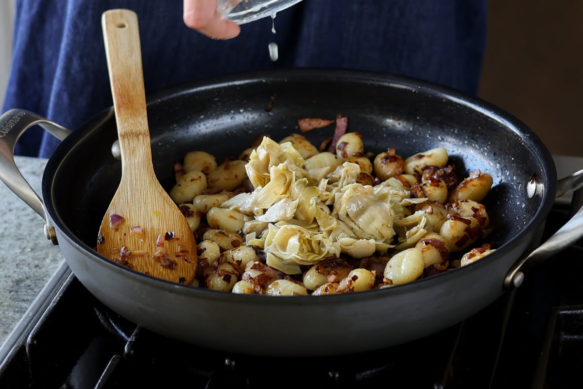 adding artichokes to the pan