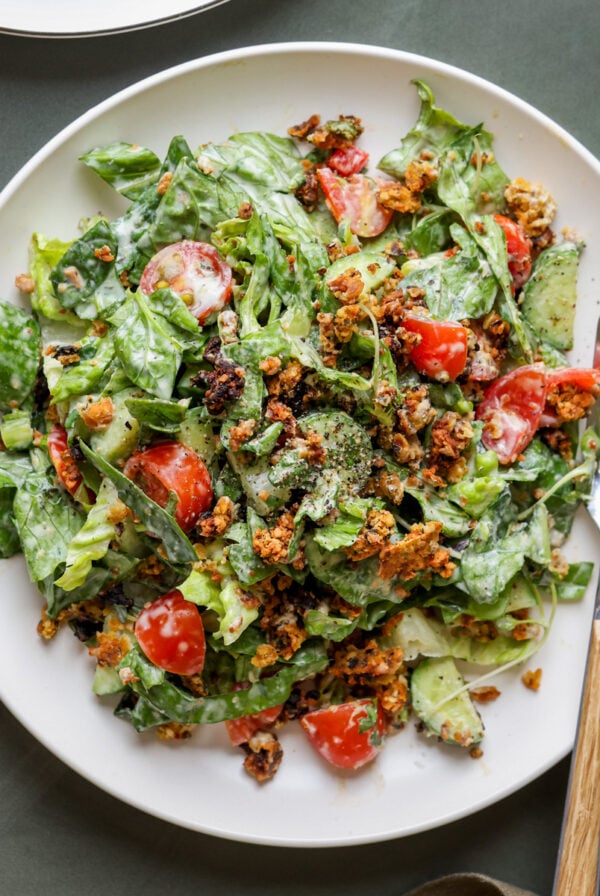summer spinach salad with chickpea olive crumbles on a plate with a fork