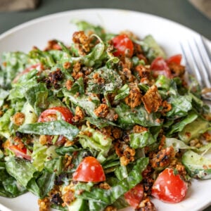 summer spinach salad with chickpea olive crumbles on a plate with a fork
