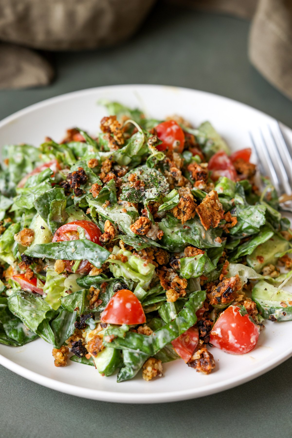 summer spinach salad with chickpea olive crumbles on a plate with a fork