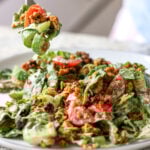 fork taking a bite of summer spinach salad with chickpea olive crumbles