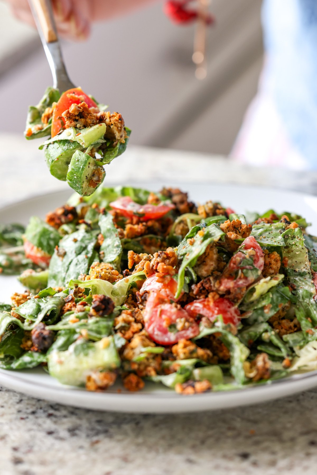 fork taking a bite of summer spinach salad with chickpea olive crumbles